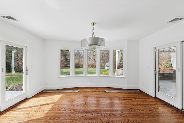 unfurnished dining area with wood finished floors, baseboards, and visible vents