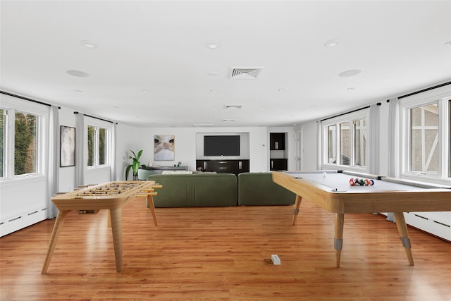 game room featuring light wood-style flooring, a baseboard heating unit, and visible vents