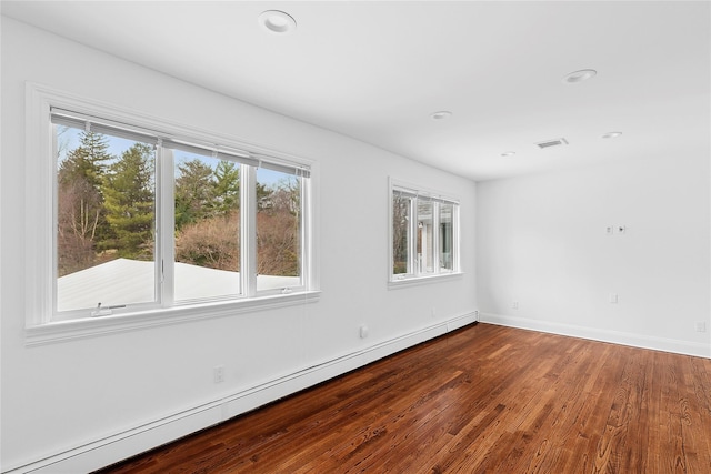 empty room with baseboard heating, baseboards, recessed lighting, visible vents, and wood finished floors