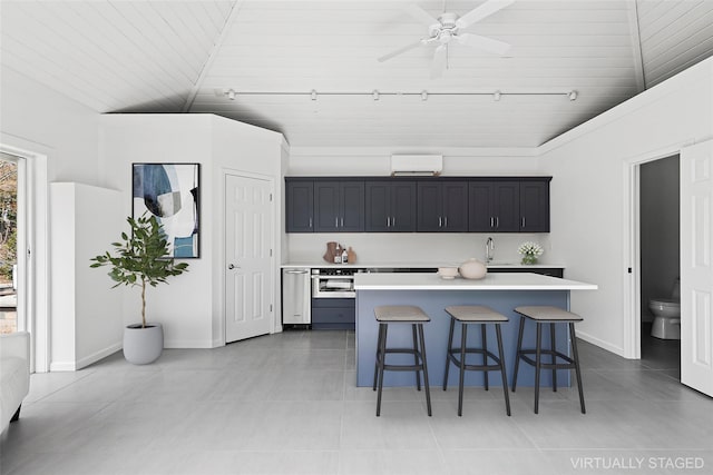 kitchen with ceiling fan, a kitchen island, a breakfast bar, light countertops, and lofted ceiling