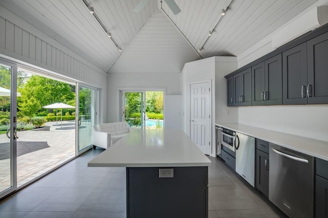 kitchen featuring track lighting, a center island, light countertops, stainless steel dishwasher, and lofted ceiling