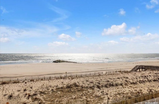 property view of water with fence and a beach view