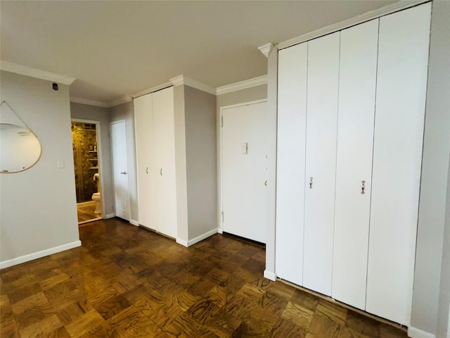 unfurnished bedroom featuring baseboards, multiple closets, and ornamental molding