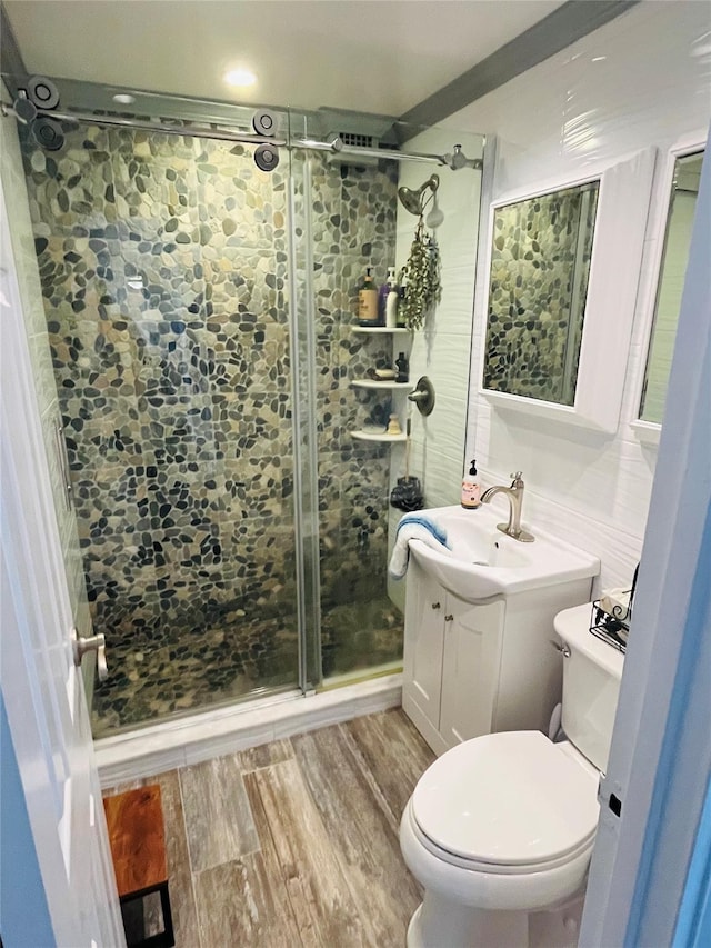 bathroom with toilet, a stall shower, wood finished floors, and vanity