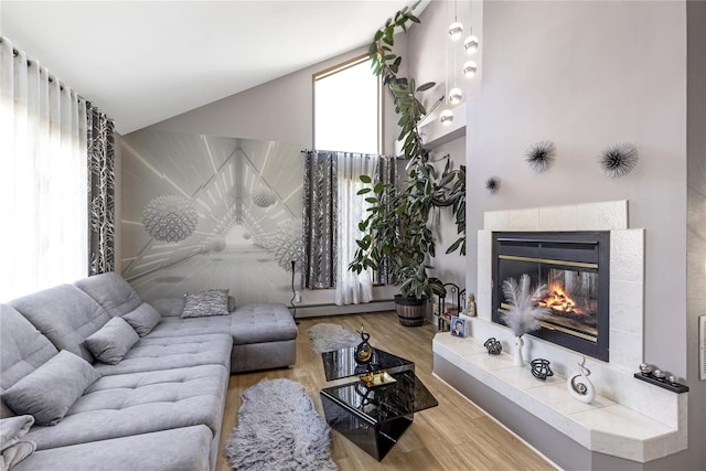 living room featuring baseboard heating, vaulted ceiling, wood finished floors, and a tile fireplace