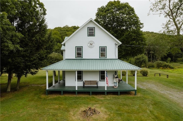 back of house with metal roof, a porch, a lawn, and dirt driveway