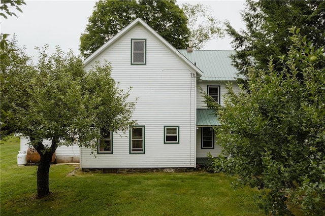 rear view of house with metal roof and a lawn