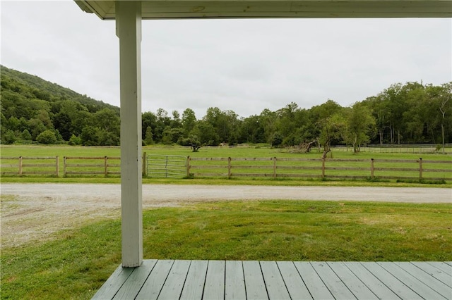 wooden terrace with a yard, fence, and a rural view