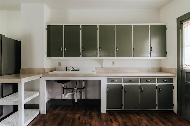kitchen with green cabinetry, dark wood-style flooring, light countertops, and a sink