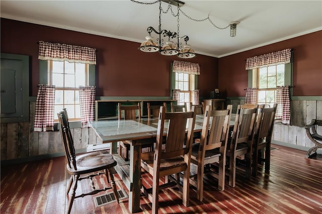 dining space featuring electric panel, a chandelier, a wainscoted wall, and wood finished floors