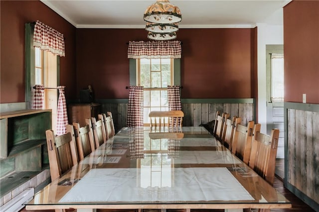 dining area with ornamental molding and a wainscoted wall
