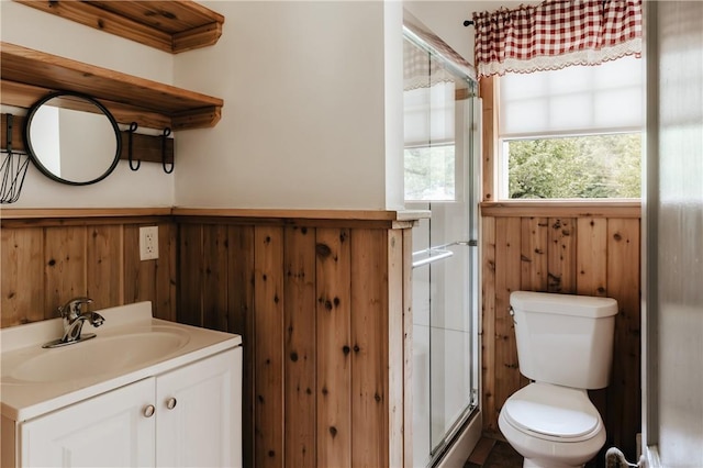 bathroom featuring toilet, a stall shower, wood walls, and vanity