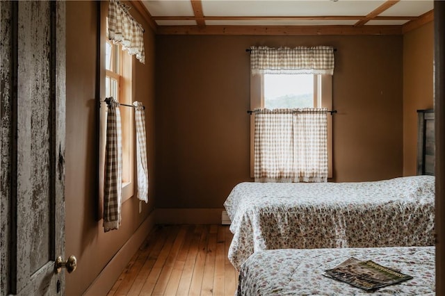 bedroom with coffered ceiling and hardwood / wood-style floors