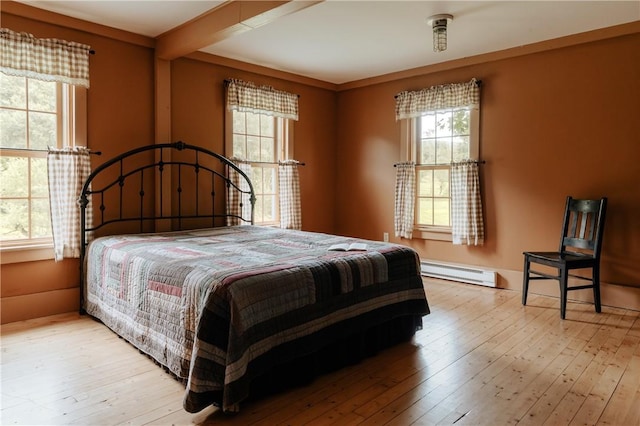 bedroom featuring hardwood / wood-style flooring, multiple windows, a baseboard heating unit, and beam ceiling