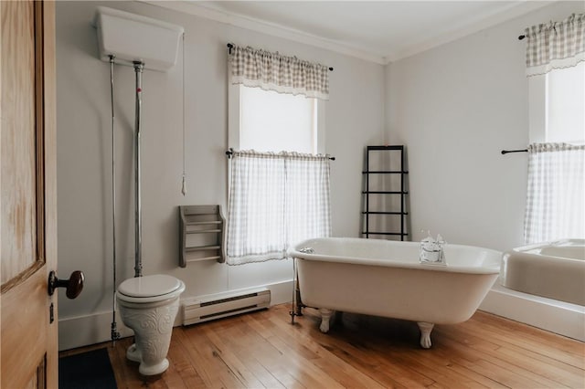 bathroom featuring baseboard heating, a freestanding bath, a healthy amount of sunlight, and hardwood / wood-style flooring