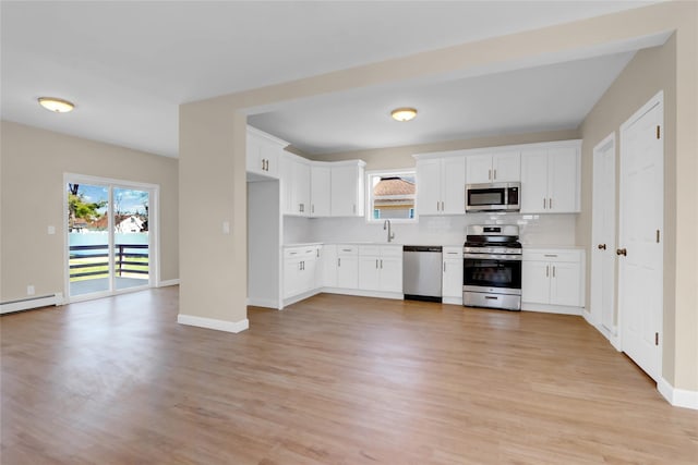 83 Fairview Ave, Islip Terrace, NY 11752 - kitchen with light countertops, white cabinetry, stainless steel appliances, backsplash, and light wood-style flooring