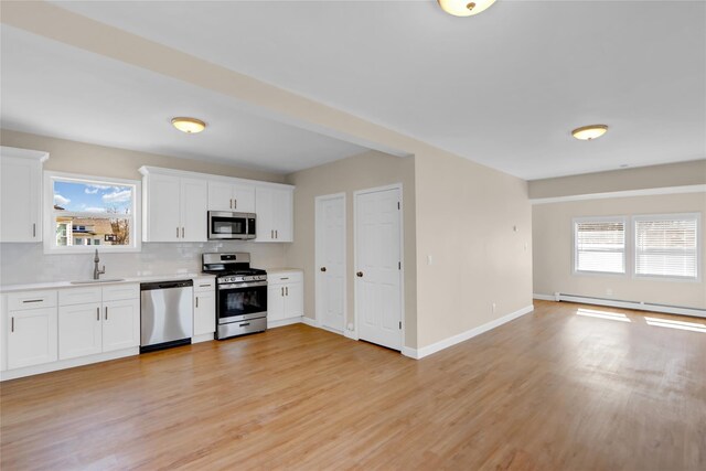 83 Fairview Ave, Islip Terrace, NY 11752 - kitchen with baseboard heating, light countertops, light wood-style floors, stainless steel appliances, and a sink