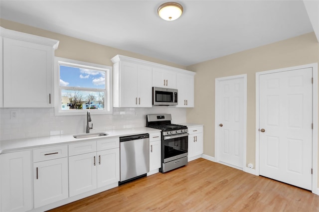 83 Fairview Ave, Islip Terrace, NY 11752 - kitchen with white cabinetry, light countertops, a sink, stainless steel appliances, and decorative backsplash