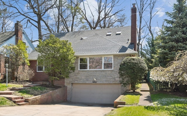 view of front of property with an attached garage, a chimney, roof with shingles, and stone siding
