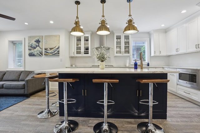 kitchen featuring stainless steel microwave, a center island, wood finished floors, and a sink