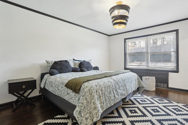 bedroom with radiator heating unit, wood finished floors, crown molding, and baseboards