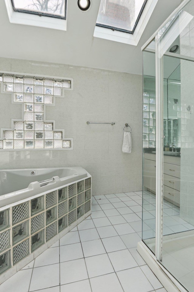 full bathroom featuring a shower stall, tile patterned flooring, tile walls, a skylight, and a garden tub