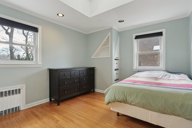 bedroom with baseboards, recessed lighting, radiator heating unit, wood finished floors, and crown molding