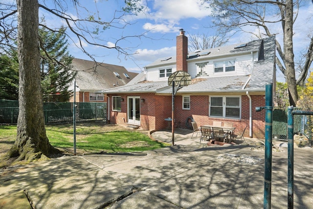 back of property featuring a chimney, brick siding, fence, and a patio