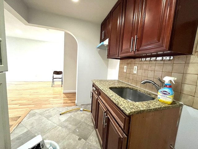 104-27 38th Ave Unit 1B, Corona, NY 11368 - kitchen with light stone countertops, arched walkways, dark brown cabinets, a sink, and decorative backsplash