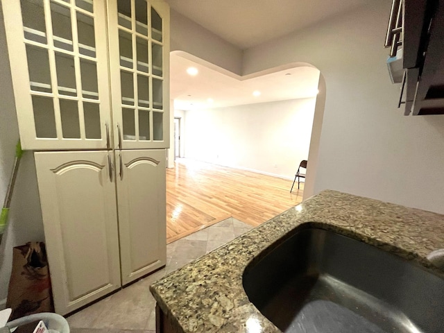 104-27 38th Ave Unit 1B, Corona, NY 11368 - kitchen featuring glass insert cabinets, arched walkways, a sink, recessed lighting, and stone counters