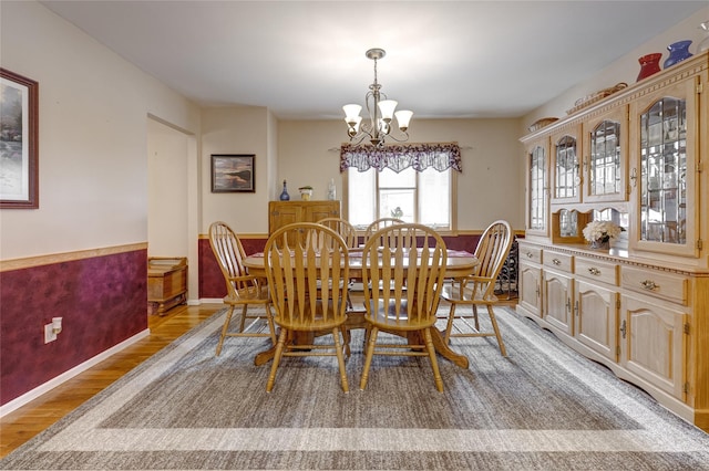 dining space featuring light wood finished floors, a notable chandelier, and wainscoting