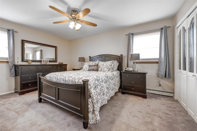 bedroom with light colored carpet, a closet, a baseboard heating unit, and a ceiling fan