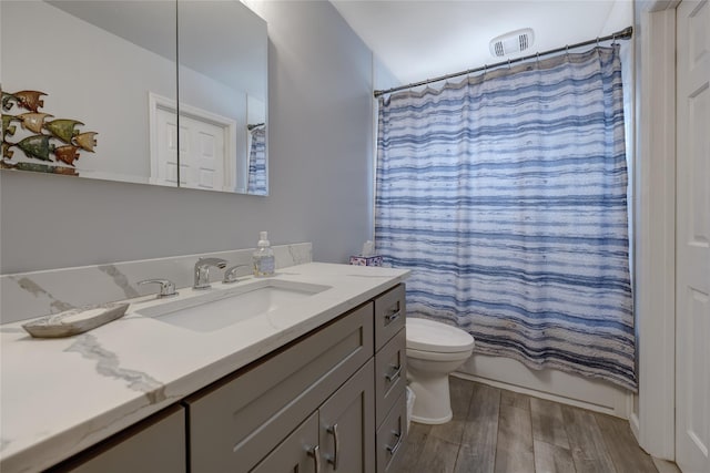bathroom featuring toilet, wood finished floors, vanity, and visible vents