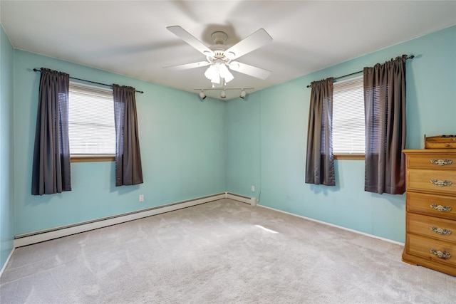 carpeted spare room featuring baseboards, a baseboard heating unit, a ceiling fan, and a healthy amount of sunlight