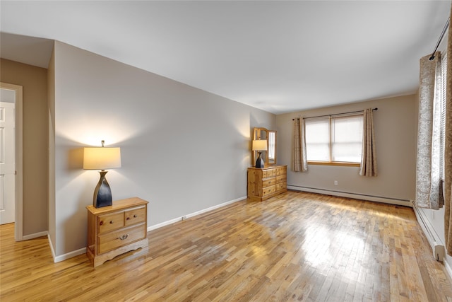 unfurnished bedroom featuring baseboard heating, light wood-style floors, and baseboards