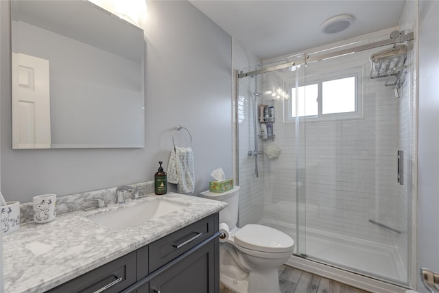 bathroom featuring a shower stall, wood finished floors, vanity, and toilet
