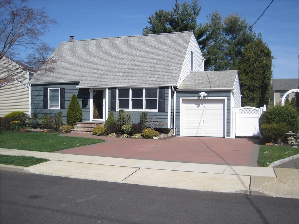 3865 New York Ave, Seaford, NY 11783 - cape cod-style house with roof with shingles, a garage, concrete driveway, and a gate