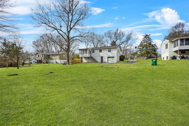 view of yard featuring stairway, driveway, and an attached garage