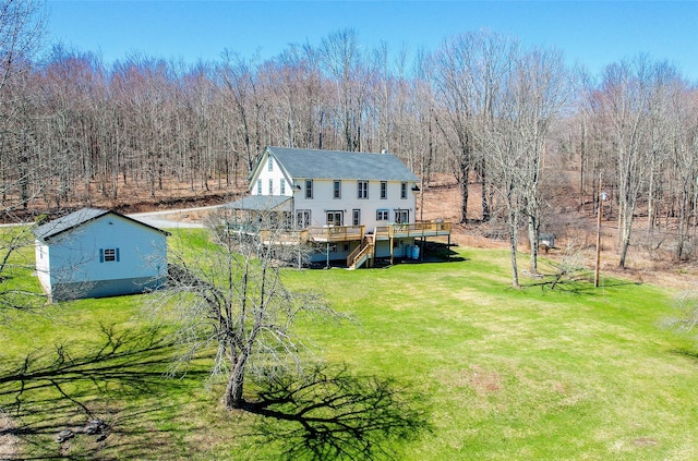 back of house with a view of trees, a wooden deck, a yard, and stairway