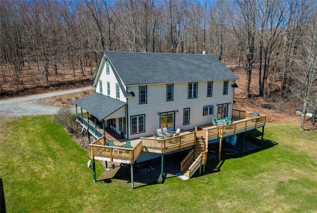back of property featuring a lawn, a wooden deck, a shingled roof, and a chimney