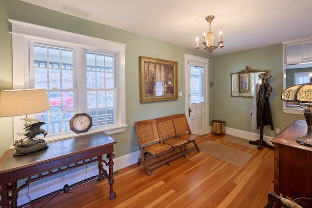 entryway with baseboards, a notable chandelier, visible vents, and light wood-type flooring