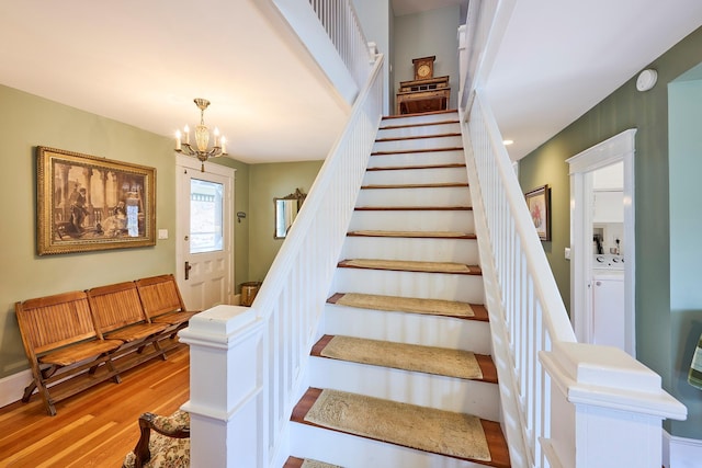 stairway with separate washer and dryer, a notable chandelier, and wood finished floors