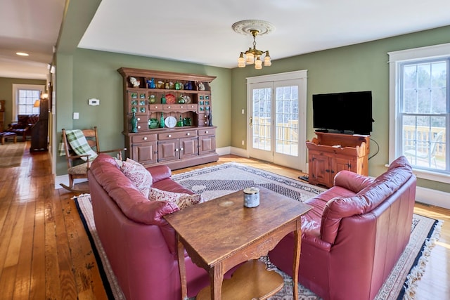 living area featuring a healthy amount of sunlight, baseboards, and hardwood / wood-style flooring