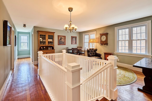 interior space with dark wood-style flooring, baseboards, an inviting chandelier, and plenty of natural light