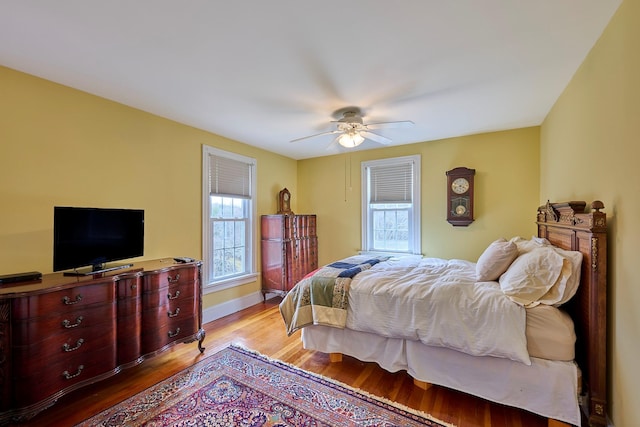 bedroom with baseboards, ceiling fan, multiple windows, and wood finished floors