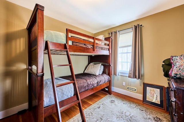 bedroom with baseboards, wood finished floors, and visible vents