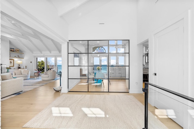interior space featuring high vaulted ceiling, beamed ceiling, and wood finished floors