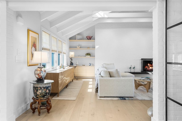 interior space featuring vaulted ceiling with beams, built in features, light wood-style flooring, and a fireplace