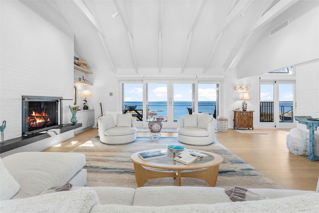 living area with beamed ceiling, a large fireplace, wood finished floors, and high vaulted ceiling