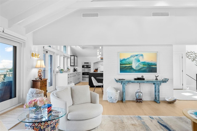 living area with light wood-style floors, lofted ceiling with beams, and visible vents